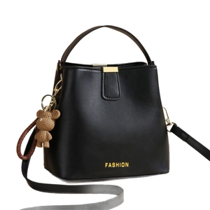 Sac seau élégant en cuir noir avec détails dorés et un porte-clé ours tressé chic