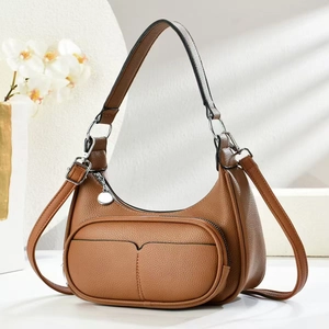 Detailed view of brown litchi leather crescent bag with adjustable strap and silver hardware