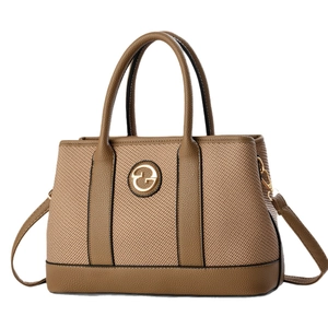 Brown leather and woven fabric shoulder bag with golden round logo on white background