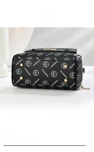 Detailansicht des Taschenbodens in Schwarz mit goldenen Füßen und Logo-Druck