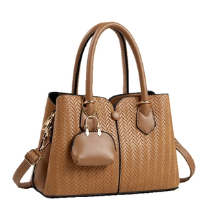 Brown faux leather handbag with V-shaped woven texture and small hanging pouch charm