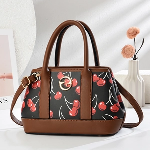 Detail of cherry print tote bag with brown leather trim and metallic circular G-buckle