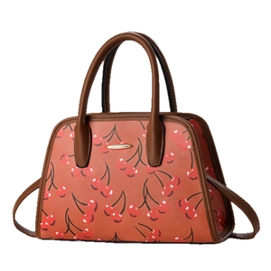 Chic tote bag with red cherry prints and brown leather straps in a 45-degree angle view