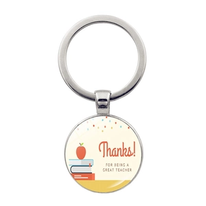 Macro shot of silver metal keychain with colorful book illustration and teacher thank you note