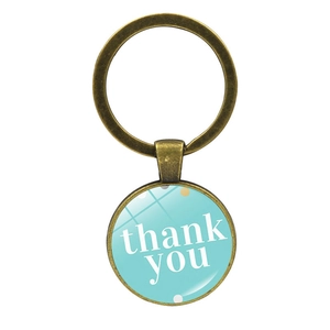 Gros plan d'un porte-clés bronze vintage avec cabochon 'thank you' bleu à pois