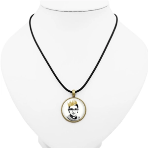 Detail of vintage round pendant featuring RBG portrait with a gold crown on black cord
