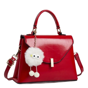 Rote Lackleder-Handtasche mit goldener Hardware und weißem Monster-Anhänger auf Weiß
