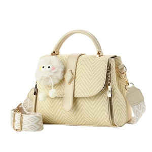 Beige woven crossbody bag with wide jacquard strap and cute plush charm on white background