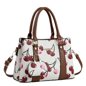 White cherry print tote bag with brown leather handles and matching mini coin purse charm