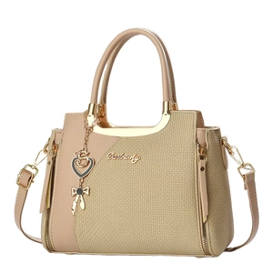 Elegant tan paneled women's handbag with gold hardware and heart bow charms