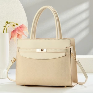 Detail of the woven fabric texture and smooth leather handle on a cream handbag