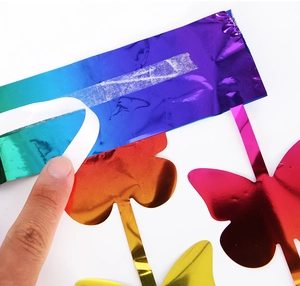 Detail of colorful gradient butterfly foil curtain with adhesive backing being peeled