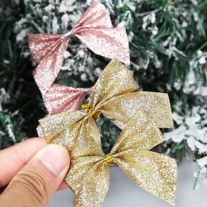 Nahaufnahme glitzernder Weihnachtsschleifen in Gold und Rosa auf verschneiten Zweigen