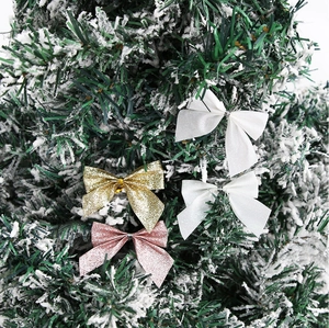 Nahaufnahme glitzernder Weihnachts-Schleifen in Weiß, Gold und Rosa am Tannenbaum