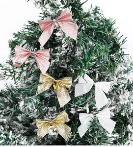 Detail von rosa und champagnerfarbenen Glitzer-Weihnachtsschleifen auf verschneiten Ästen