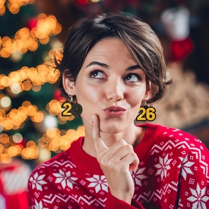 Détail de boucles d'oreilles horloge 2026 pailletées portées dans une ambiance de fête