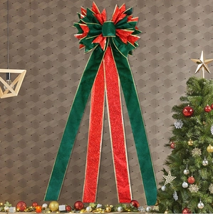 Detail of green velvet and red glitter Christmas bow with gold edges for tree topper