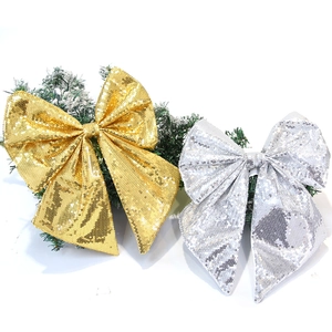 Dettaglio di grandi fiocchi natalizi con paillettes oro e argento su rami innevati