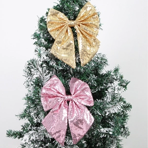Dettaglio di fiocchi di paillettes rosa e oro su un ramo di albero di Natale innevato