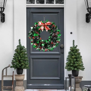Close-up of a green Christmas wreath with a red snowflake bow on a dark entry door