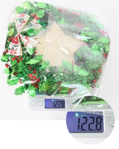 Weight measurement of a Christmas wreath with red berries and bow in protective packaging