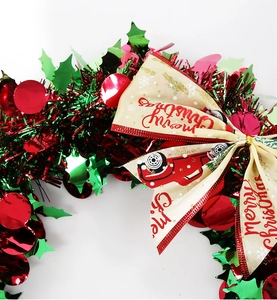 Close-up of Christmas tinsel wreath featuring red truck ribbon and Merry Christmas text