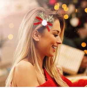 Détail d'une pince à cheveux de Noël avec bois de renne, nœud en velours rouge et paillettes