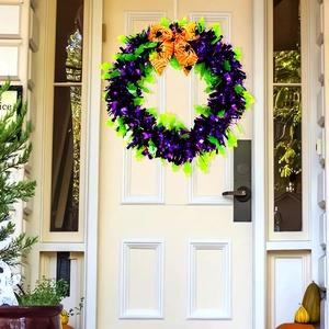 Detail of Halloween tinsel wreath with purple green fringe and orange spiderweb bow