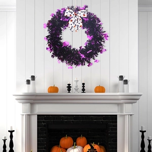 Detail of Halloween wreath with purple bats, black tinsel, and festive bow on a fireplace