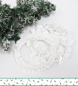 Close-up of white sequin heart garlands and snow-effect pine branches for Christmas decor