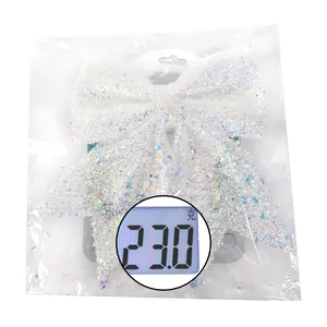 Detalle de lazo navideño blanco brillante con indicación de peso de 23,0g en la báscula
