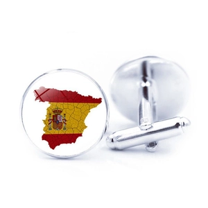 Detailed close-up of round silver cufflinks with Spanish flag and map on glass surface