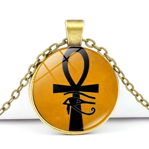 Macro shot of Egyptian Ankh and Eye of Horus glass pendant in vintage gold alloy finish