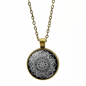 Detail of vintage bronze mandala necklace featuring a glass dome and geometric pattern