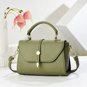 Macro detail of green lychee leather texture and golden metal hardware on a crossbody bag