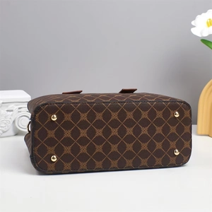 Close-up of handbag base featuring vintage monogram pattern and gold protective studs