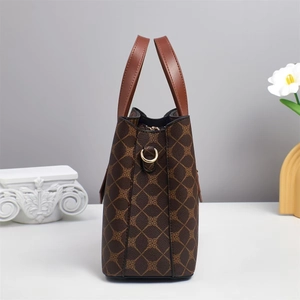Detail view of large dark brown tote bag with quilted floral pattern and leather handles