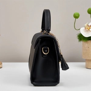 Detail of elegant black crossbody bag side view with gold D-ring and chain accent