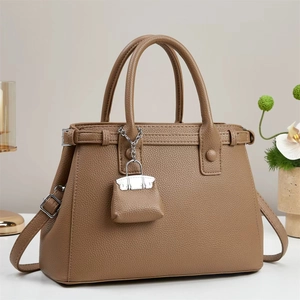 Elegant tan lychee leather handbag with dual handles and adjustable shoulder strap