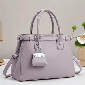 Detail of light purple lychee leather handbag with silver hardware and mini charm accessory