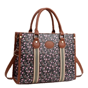 Women's black cherry print tote bag with brown leather handles and striped webbing details