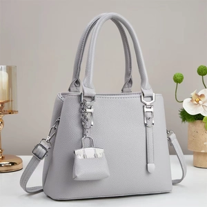 Close-up of grey pebble leather tote bag with silver hardware and mini charm