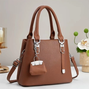 Close-up of brown litchi grain leather tote bag with silver hardware and chain detail