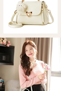 Detail of white lychee leather texture with gold hardware and plush charm on crossbody bag
