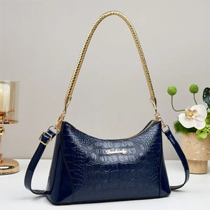 Detail of navy blue crocodile pattern leather bag with golden woven handle and brand logo
