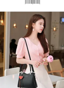 Close-up of black pebble leather handbag featuring heart charm and fashion bag engraving