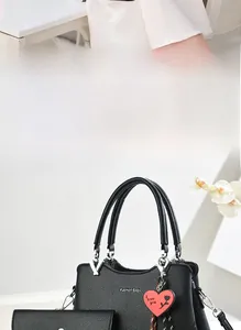 Detail of black pebbled leather tote bag with heart charm and matching wallet set