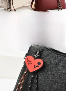 Close-up of a red heart-shaped bag charm with I love you text and black rose detail