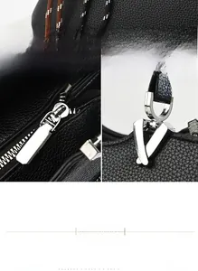 Detail of black pebbled texture fabric bag with silver V-shaped hardware and zippers