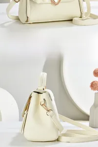 Detail of creamy white leather crossbody bag with lychee texture and gold hardware